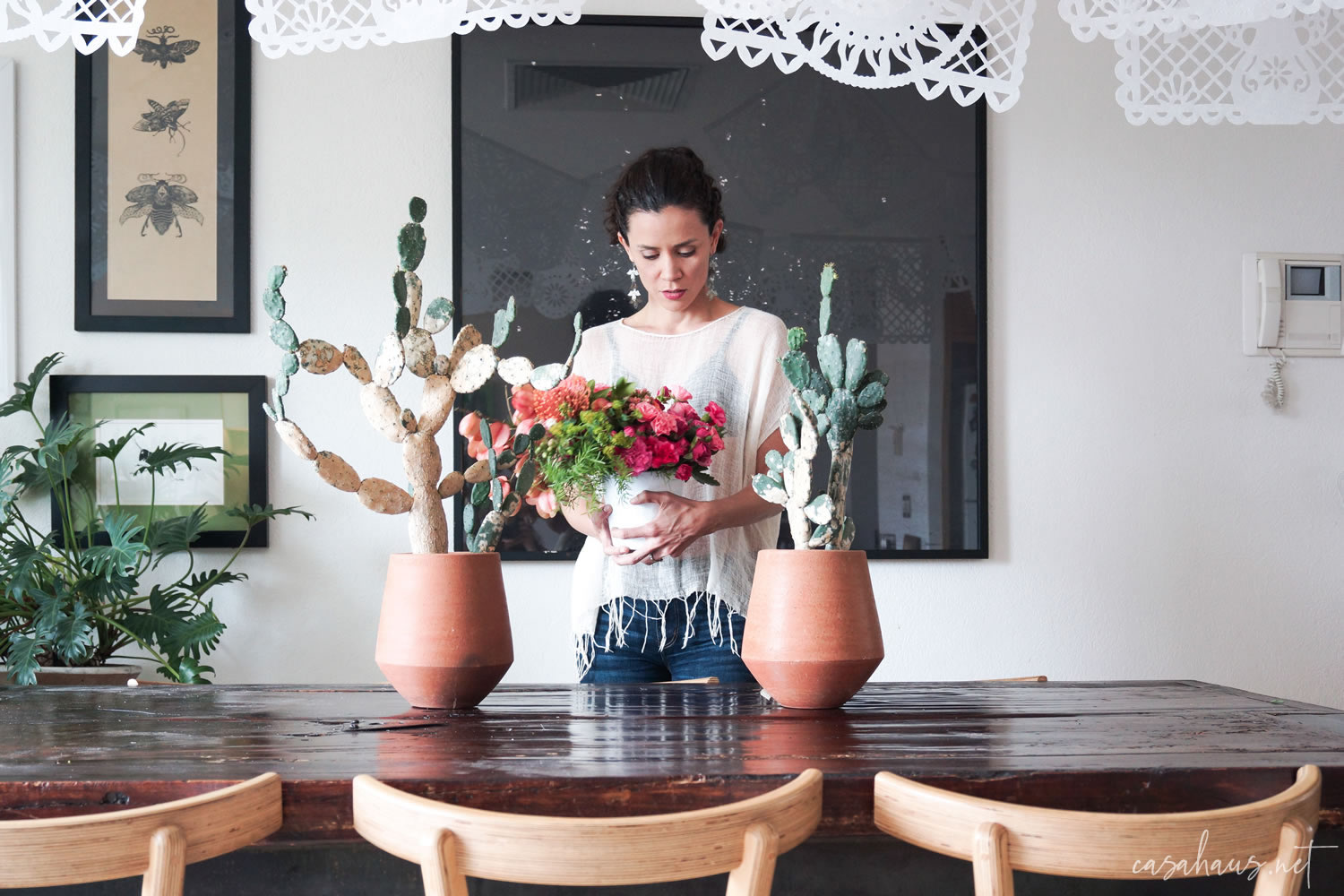Mujer joven poniendo flores sobre la mesa con nopales