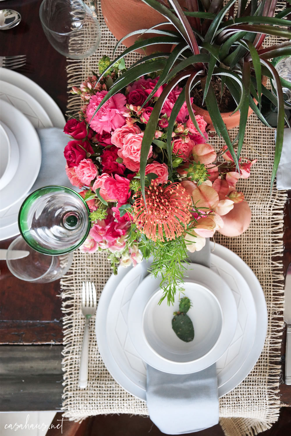 Platos puestos con nopalito, en mesa con cactus y flores rosas