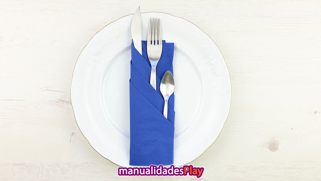 Servilleta de color azul doblada de forma elegante con cuchillo, tenedor y cuchara en su interior