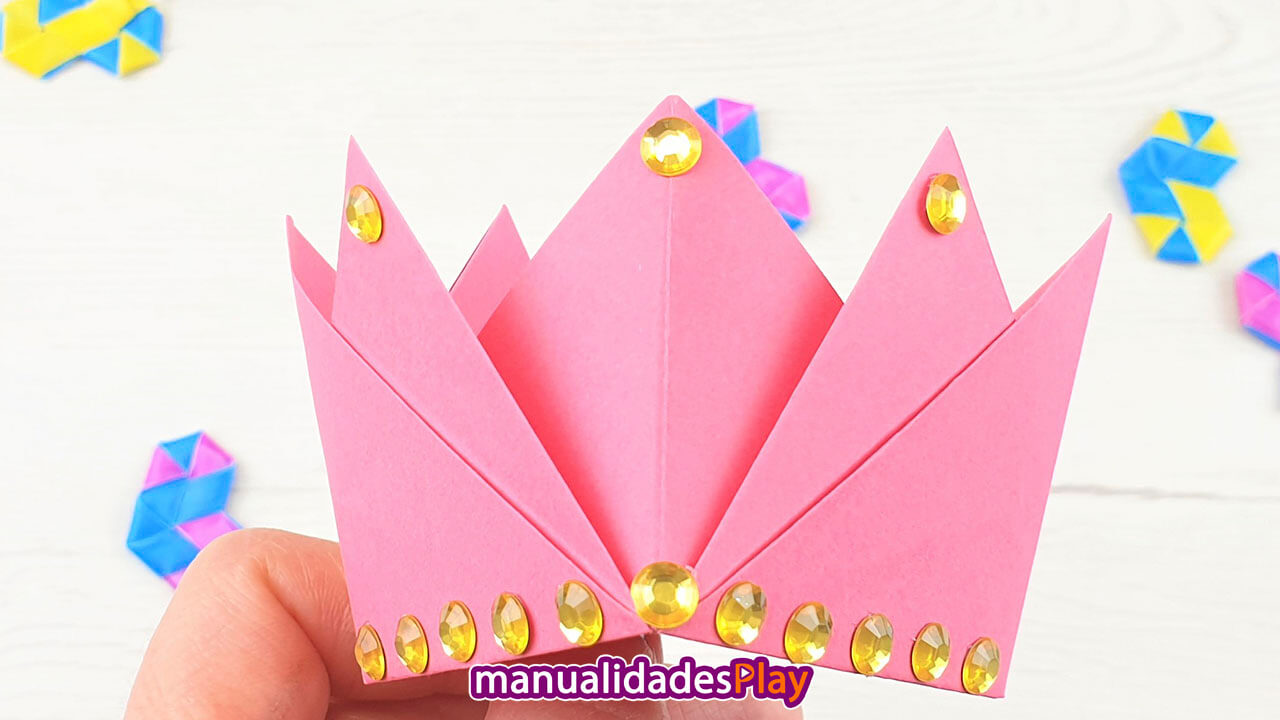 Corona de papel de color rosa con perlas