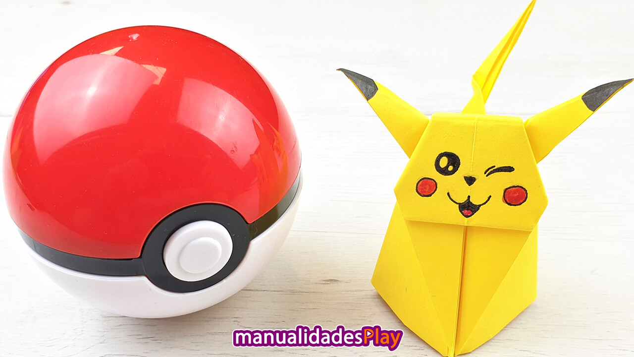 Pikachu de origami en tres dimensiones guiñando un ojo al lado de una pokeball