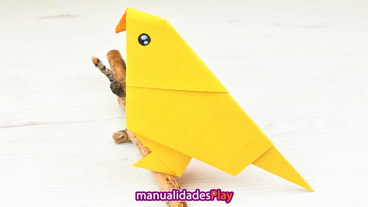 Pajaro de origami de color amarillo en una rama