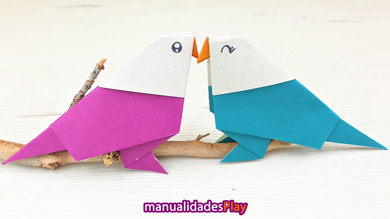 Dos pajaros de origami realizados con una hoja de papel juntado el pico